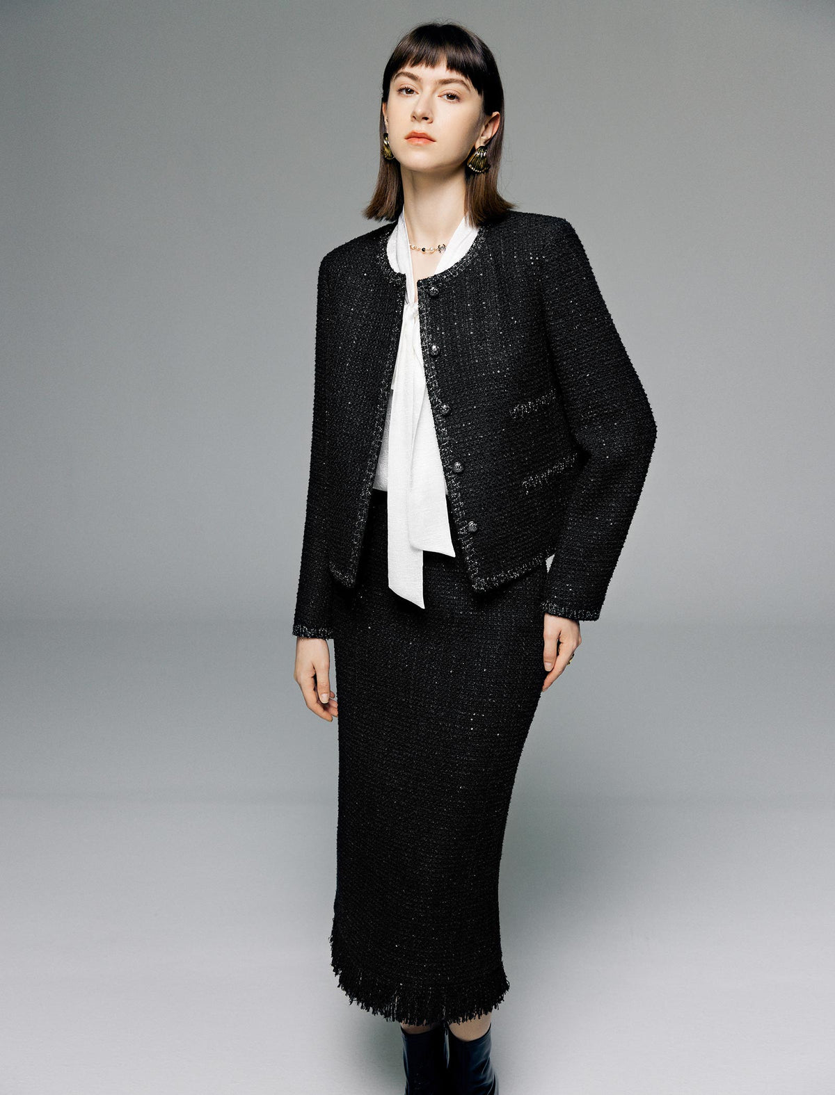 Woman wearing a black suit with a white blouse on a gray background