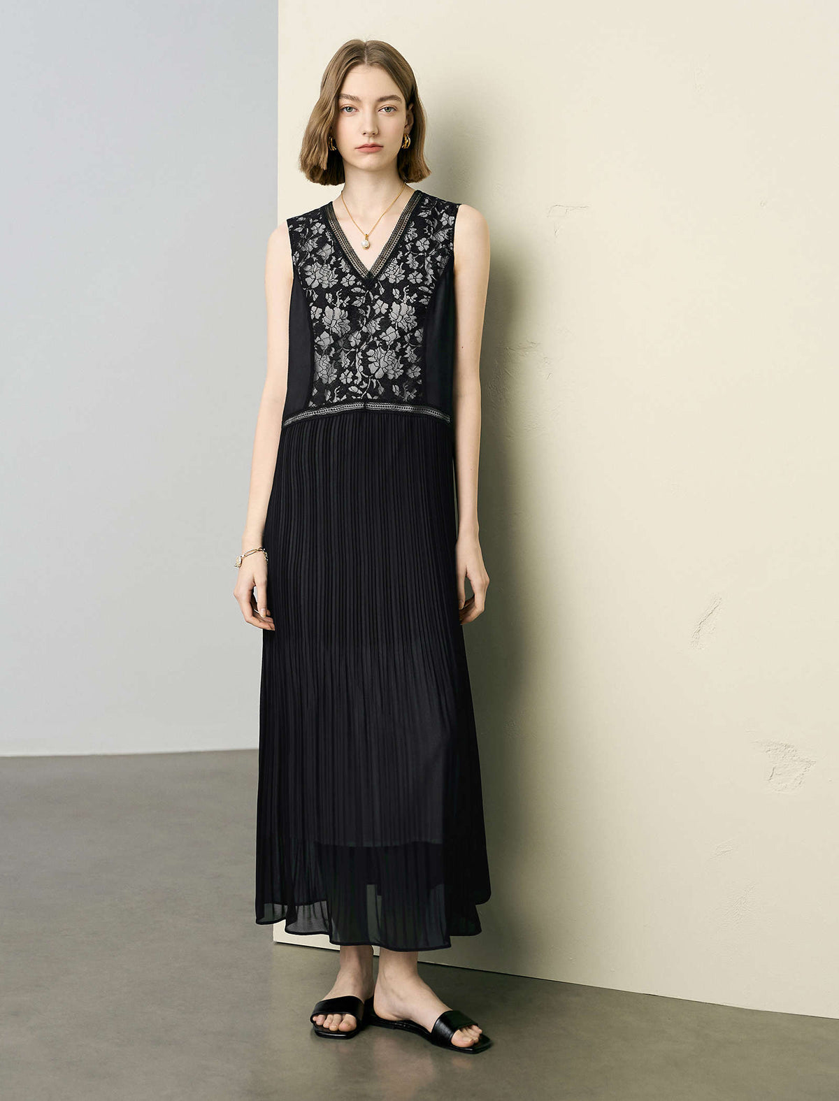 Woman wearing a black dress with floral embroidery against a plain background