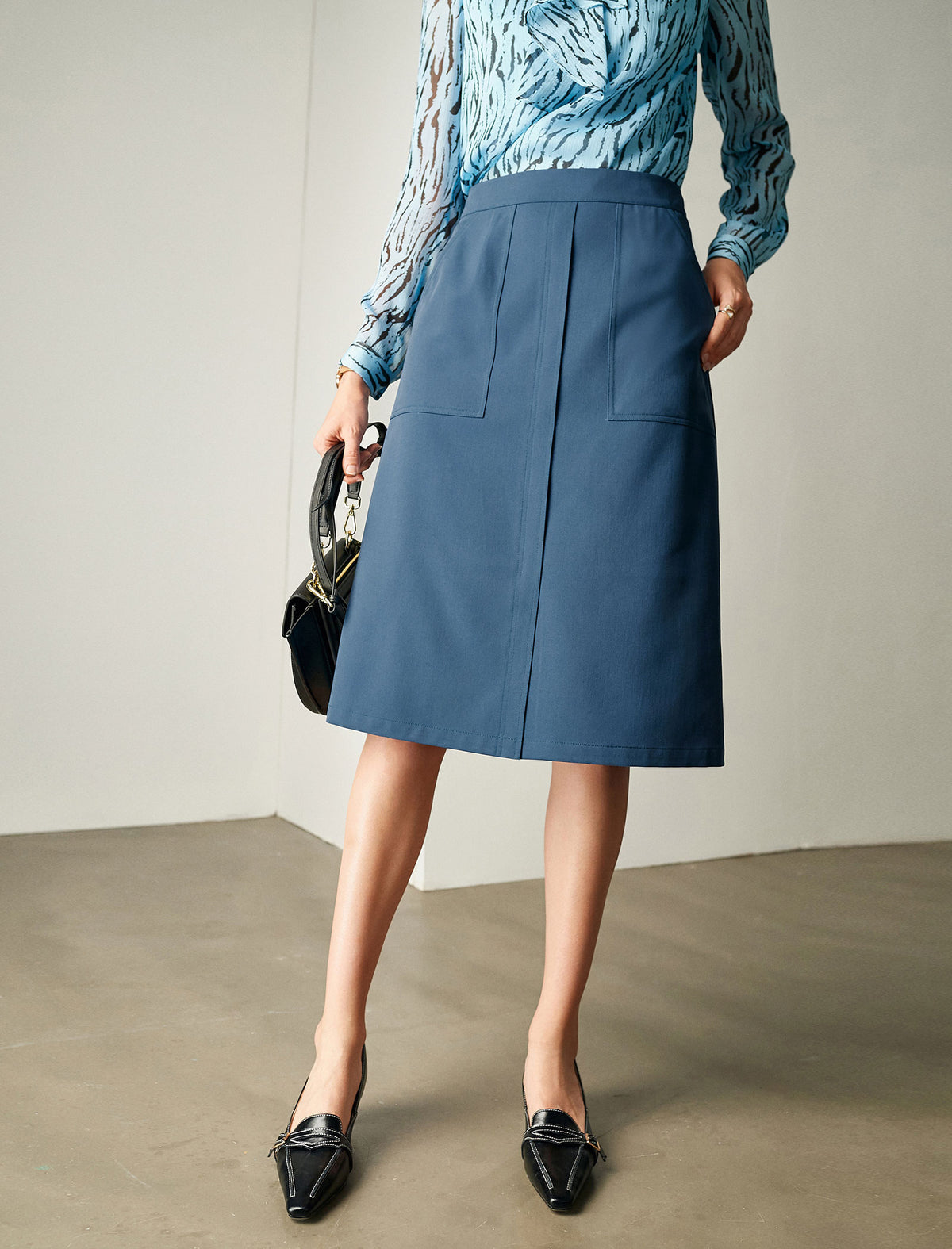 Person wearing a blue skirt with a plain background