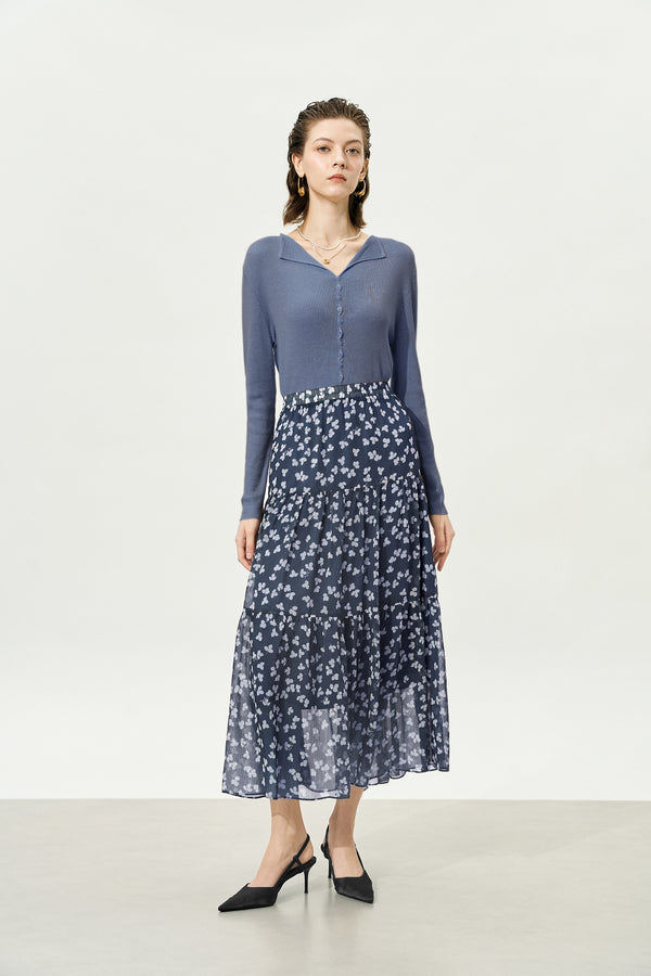 Woman wearing a blue long-sleeve top and floral skirt on a white background