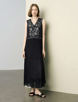 Woman wearing a black dress with floral embroidery against a plain background
