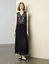 Woman wearing a black dress with floral embroidery against a plain background