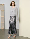 Woman wearing a silver top and black and gray patterned skirt in a minimalistic setting