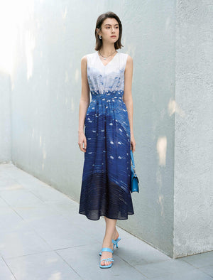 Woman wearing a blue and white dress standing against a light gray wall.