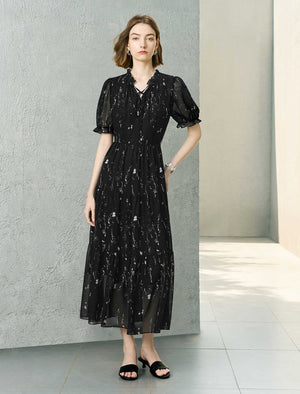 Woman wearing a black dress with white patterns in an indoor setting